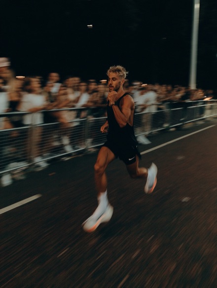 Runner sprinting from a race start in front of a crowd